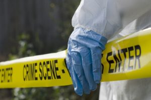 man in biohazard suit behind crime scene tape